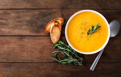 imagem mostra um prato com uma sopa de fubá em tons amarelados salpicada de salsinha e parmesão ralado