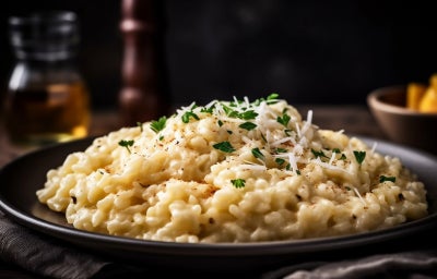 imagem mostra um prato com risoto em tons claros, pedaços de palmito e salsinha polvilhada por cima.